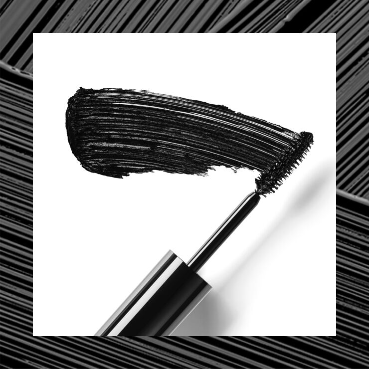 A close-up of a mascara wand with a thick stroke of black mascara on a white background.
