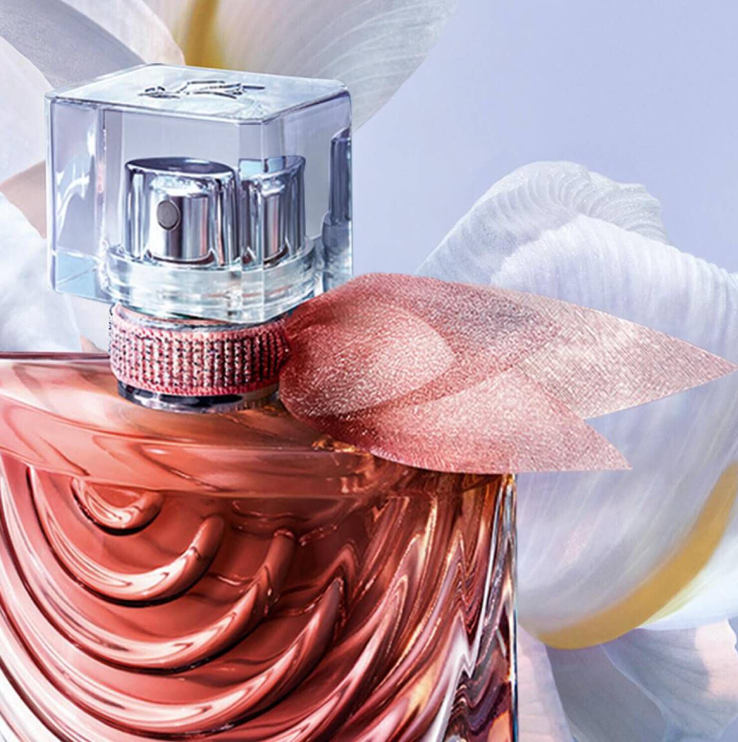 A close-up of a stylish perfume bottle with a sleek design, featuring a clear cap and decorative ribbon detail, against a soft floral background.
