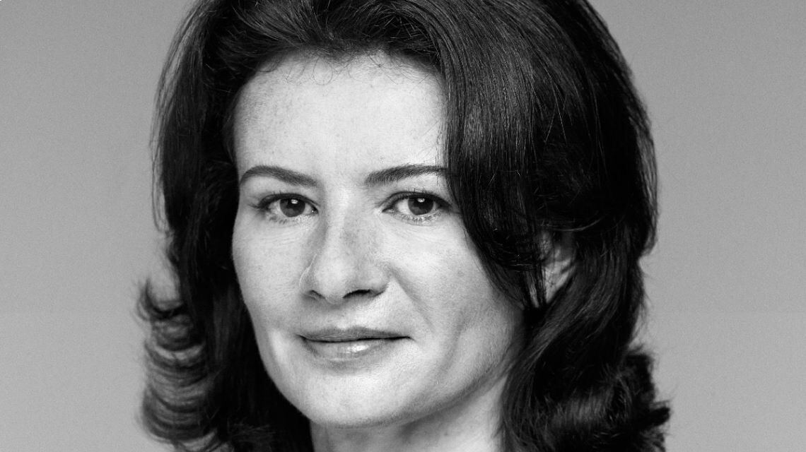 Portret van een vrouw met bruin, golvend haar en een vriendelijke uitstraling, gefotografeerd in zwart-wit.