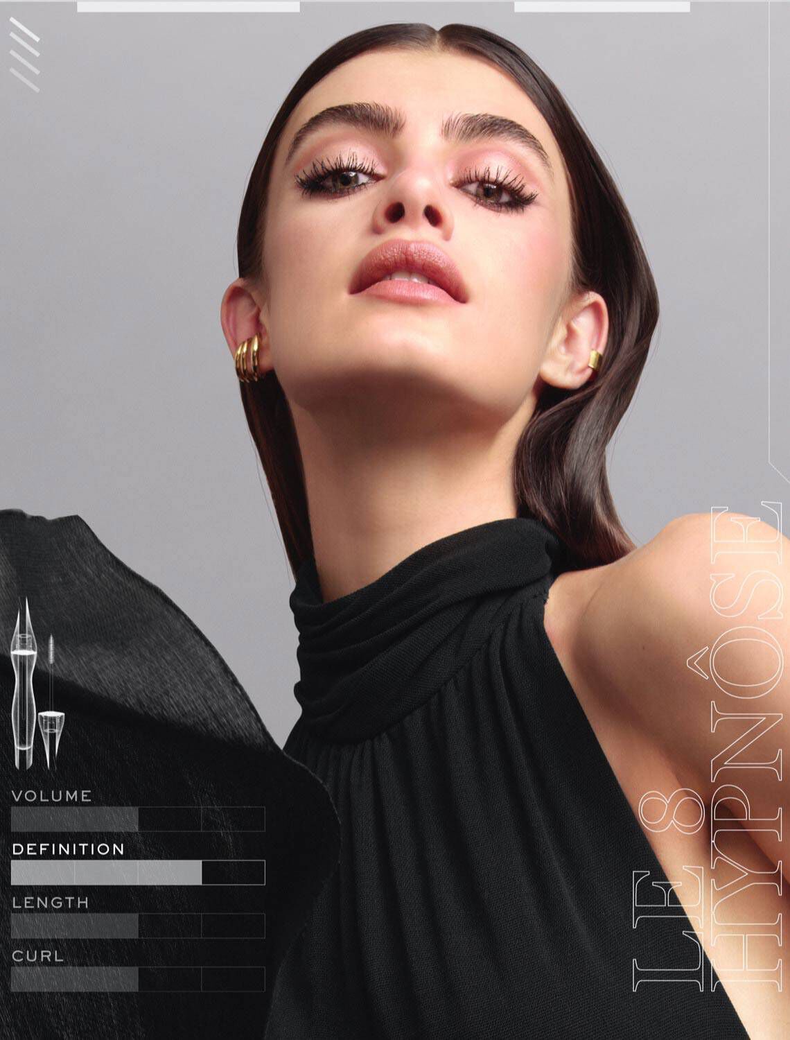 Model met een glamoureuze uitstraling in een zwart kledingstuk, met opvallende makeup en een elegante pose tegen een neutrale achtergrond.