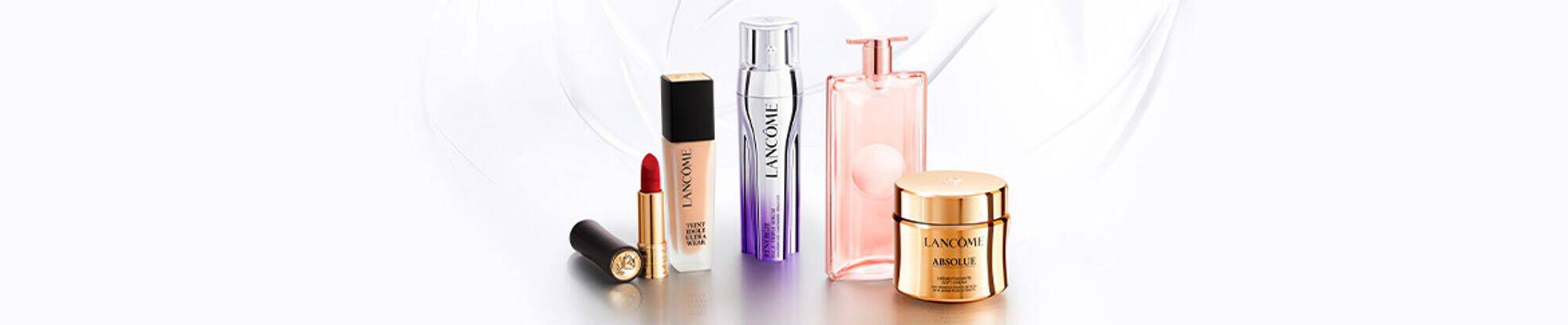 Alt-tekst: Een assortiment van Lancome schoonheidsproducten, waaronder lippenstift, serum, parfum en gezichtscreme, op een lichte achtergrond.