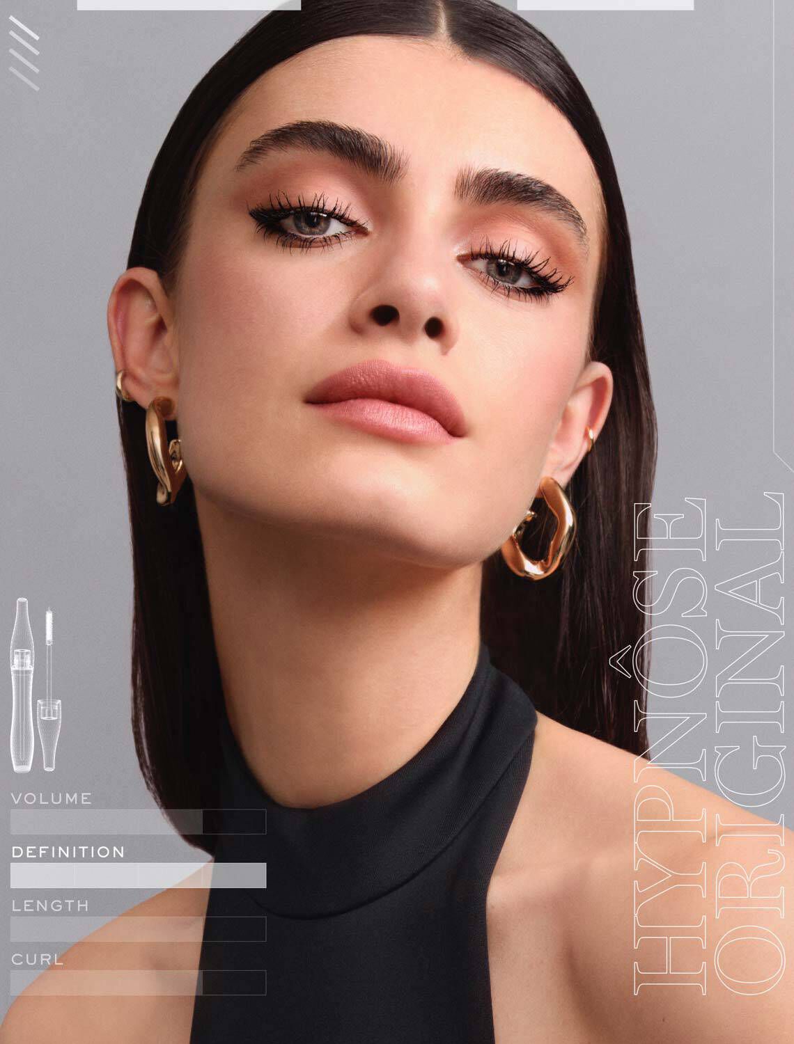 Een vrouw met een glamoureuze uitstraling heeft een stralende huid en een opvallende make-up, met lange wimpers en een elegante kapsel. Ze draagt een zwarte top en gouden oorbellen.